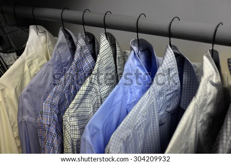 Row of dress shirts hanging on hangers in closet choice of clothing