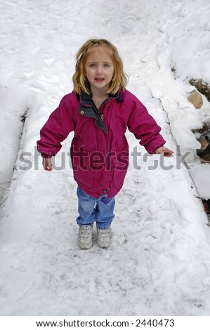 Little girl crossing foot bridge over snow and water