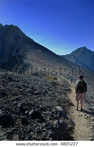 Several people walking along trail with mountains in background