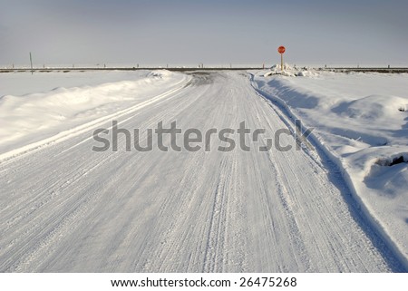 Winter country road with crossroad and car tracks in snow