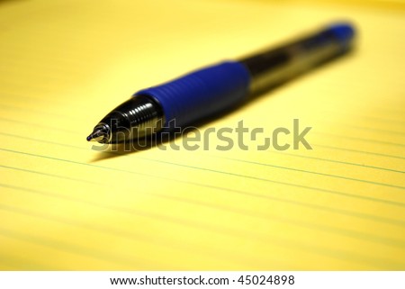 Blue pen laying on Yellow Pad of Paper