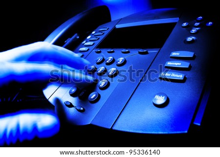 Hand dialing on a phone in a business office