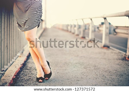 Elegant woman\'s legs standing on the bridge