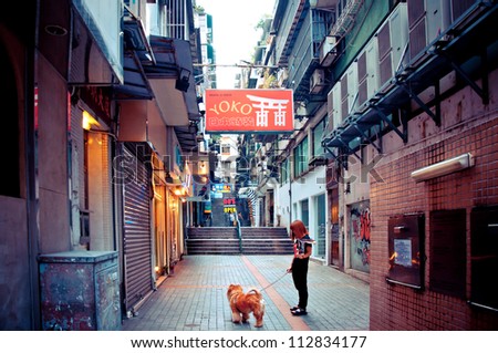 MACAU - AUGUST 1: person with dog walking in narrow street on August 1, 2012 in Macau, China. The Historic Centre of Macao was inscribed on the UNESCO World Heritage List in 2005