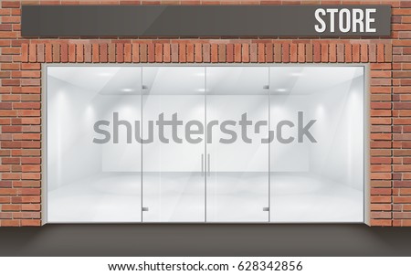 Store front with large transparent storefronts. The empty space inside is illuminated. Interior with white walls. Facade of red brick. Entrance through the large glass door.