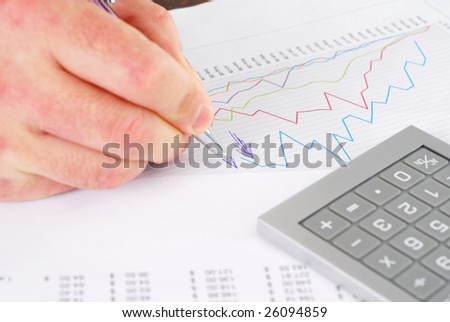Man with pen writing diagram on financial report