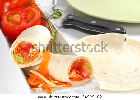Cheese and veggies in tortilla wrap with tomatoes in background
