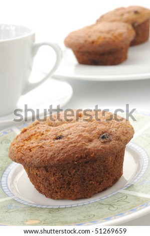 Tasty homemade muffin placed on plate with coffee and more muffins in background