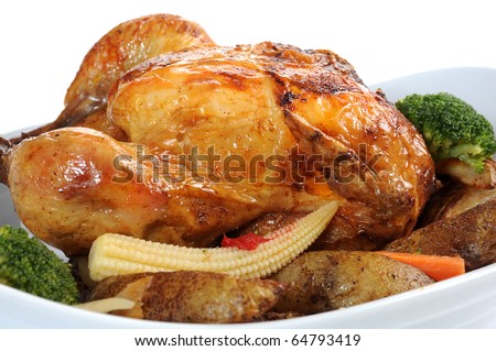 Close-up image of a roasted chicken in a dish with veggies