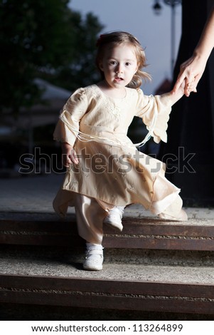 small girl in gothic dress descending steps and holding mom\'s hand