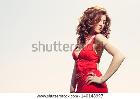 Cross processed fashion shot of sexy red hair girl wearing red dress