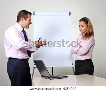 Two office workers, a man giving a presentation on a flip chart trying to convince his female colleague