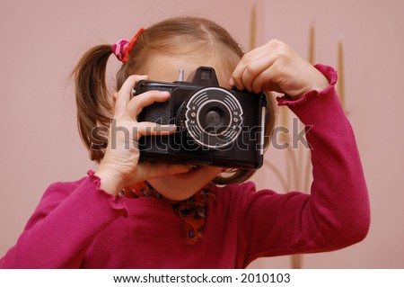 A young girl taking pictures with an very old type of camera.