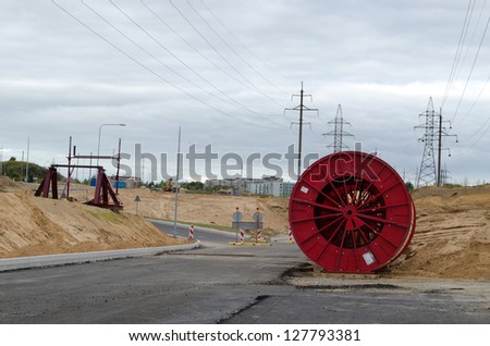 huge high voltage cable reels in power line construction site. road building work and electricity line laying underground.