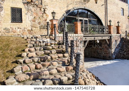 stone staircase with steel railings and light lamp leading to retro manor and snow remain in spring.