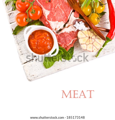meat, a large piece of fresh meat, beef, to be on the old white boards,  decorated with greens and vegetables and bowls with sauces  isolated on white background