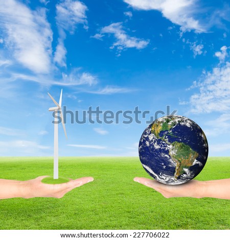 Green Earth concept,hand holding wind turbine and earth against green field and blue sky background.Elements of this image furnished by NASA