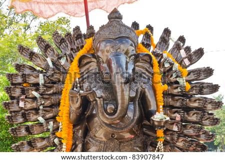 Many cast bronze hands of god Ganesha with yellow garland.