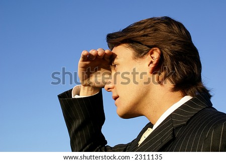 Man in pinstripe suit shields his eyes and looks at the horizon