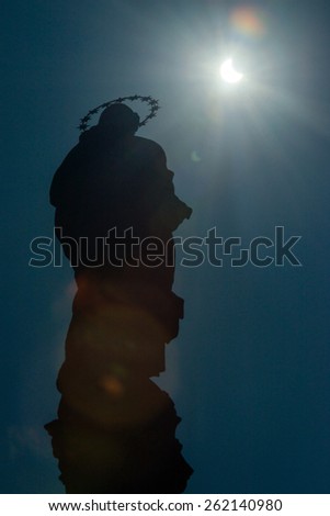 PEZINOK, SLOVAKIA - MARCH 20: Sickle-shaped sun behind a statue during a partial solar eclipse in Pezinok, Slovakia on March 20, 2015