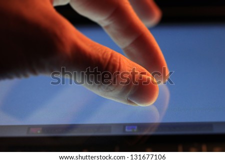 Man hand touching screen on modern digital tablet pc. Red light