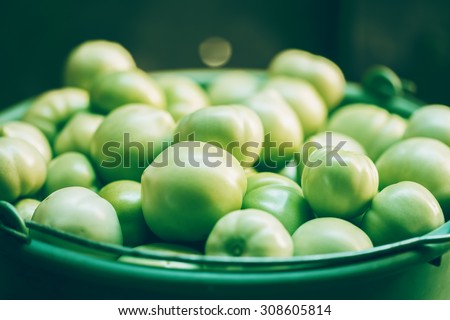 Organic green tomato in plastic bucket. Macro image.