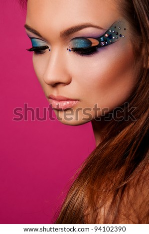 pretty brunette woman with creative makeup on pink background