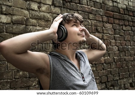 yet another brick in the wall. young man headsets music fun. lifestyle