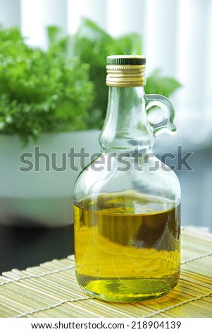 Olive oil bottle placed in kitchen with green vegetable in background