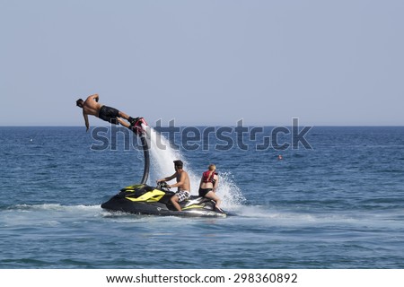 CAMYUVA, KEMER, TURKEY - JULY 16, 2015: Unidentified Turkish man demonstrates flyboard acrobatics on the beach of Camyuva. Extreme water sports are increasingly popular on the beaches of Turkey