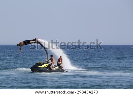 CAMYUVA, KEMER, TURKEY - JULY 16, 2015: Unidentified Turkish man demonstrates flyboard acrobatics on the beach of Camyuva. Extreme water sports are increasingly popular on the beaches of Turkey