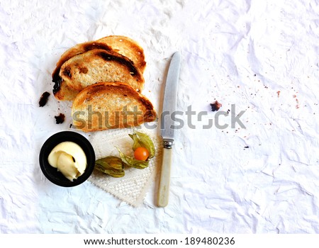 Overhead shot of a continental breakfast, home-made French melba toast with butter and physalis fruit.