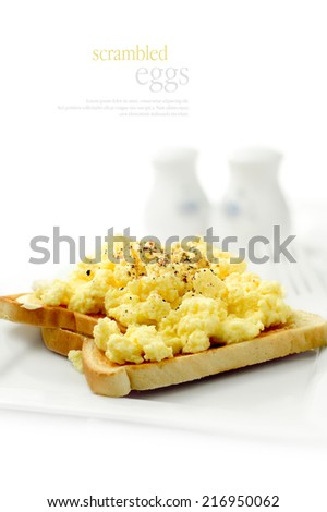 Fresh soft, fluffy scrambled eggs on wholegrain wheat toast against a white background. Copy space.