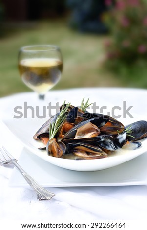 Summer mussels cooked in white wine and garlic sauce with a rosemary herb garnish. Copy space.