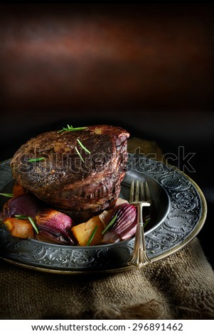 Creatively lit beef brisket in a rustic setting with roasted root vegetables of buttersquash, carrot and onions. Sunday lunch concept image, perfect for your restaurant menu cover design. Copy space.
