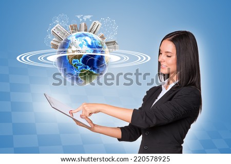 Beautiful businesswoman in suit using tablet. Earth with buildings and wire-frame spheres on blue background. Element of this image furnished by NASA