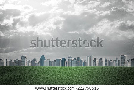 Evening city. Buildings and green grass field