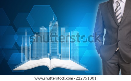 Businessman in suit standing and holds hands in pockets. Glowing wire-frame buildings on open empty book as backdrop