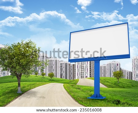 Road running through green hills leading toward city, Blank billboard and tree on foreground. High-rise buildings as backdrop