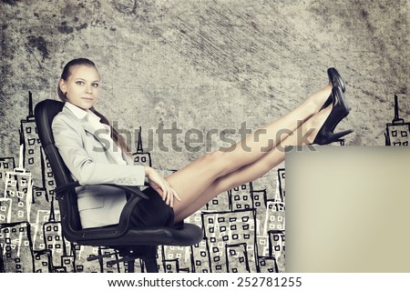 Businesswoman in office chair, looking at camera, with her feet up on anything, in front of scratched wall with sketch of city