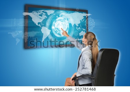 Businesswoman operating touch screen interface with world map, on blue background