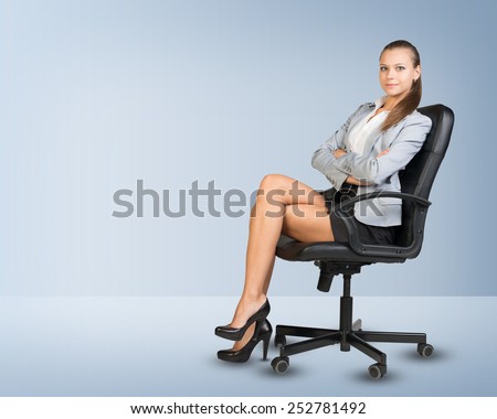 Businesswoman sitting on office chair in empty room, looking at camera
