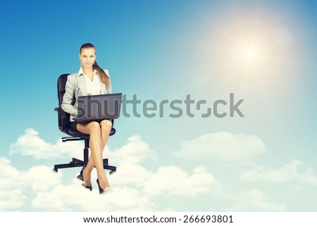 Beautiful businesswoman in suit sitting on office chair and holding open laptop, leaning back, smiling. Front view