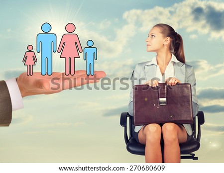 Young woman sitting in chair and looking to left at mans hand holding abstract figures of people