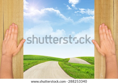 Humans hands and landscape under blue sky with clouds