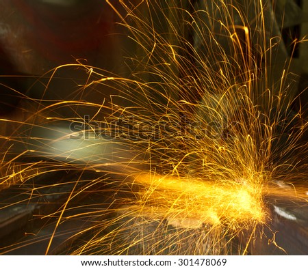 Grinding of steel sheets with electrical grinder. Long lines of flying hot sparkles deflected by some obstacles