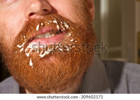 Very red beard male with a filth on the mustache and the beard in white color, could be a cream or milk or yogurt