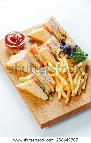 Ham sandwiches and french fries on a wooden stand and a white background