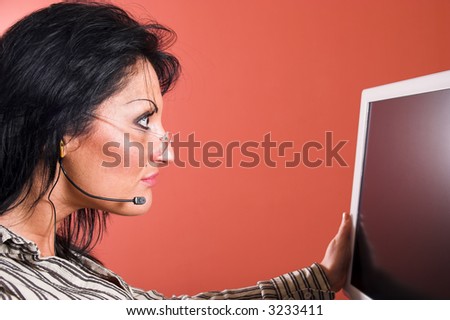 Surprised woman with headset looking at the computer monitor