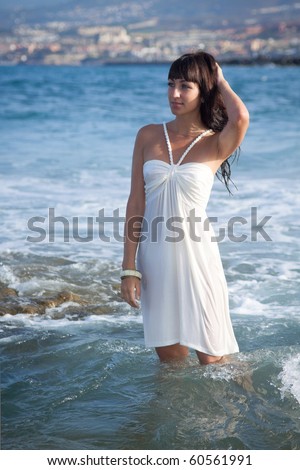 Attractive brunette model standing in water in wet white dress. Southern Tenerife, Canary Islands.